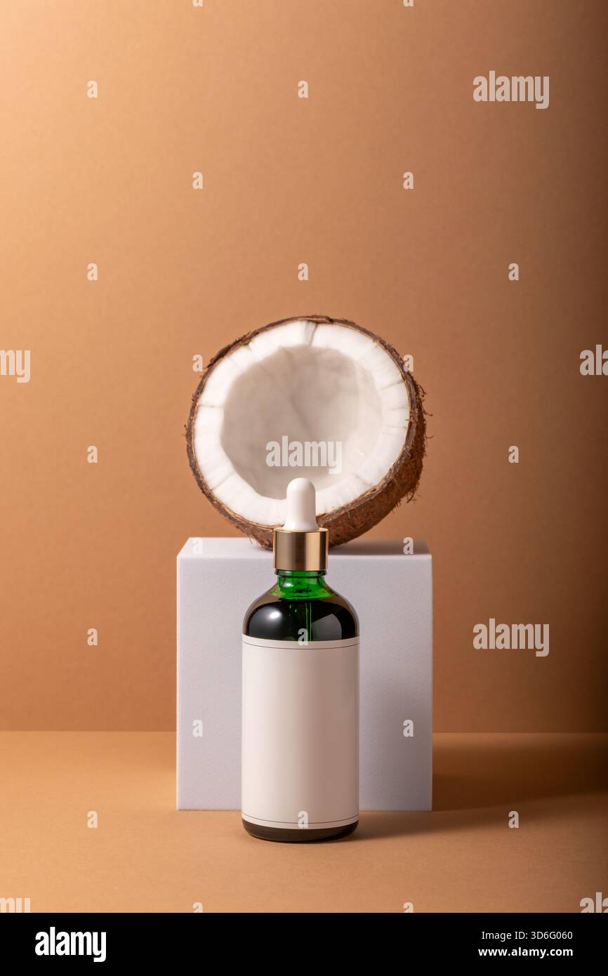 Noix de coco fissurée sur support blanc avec petite bouteille. Concept de maquette minimal. Banque D'Images