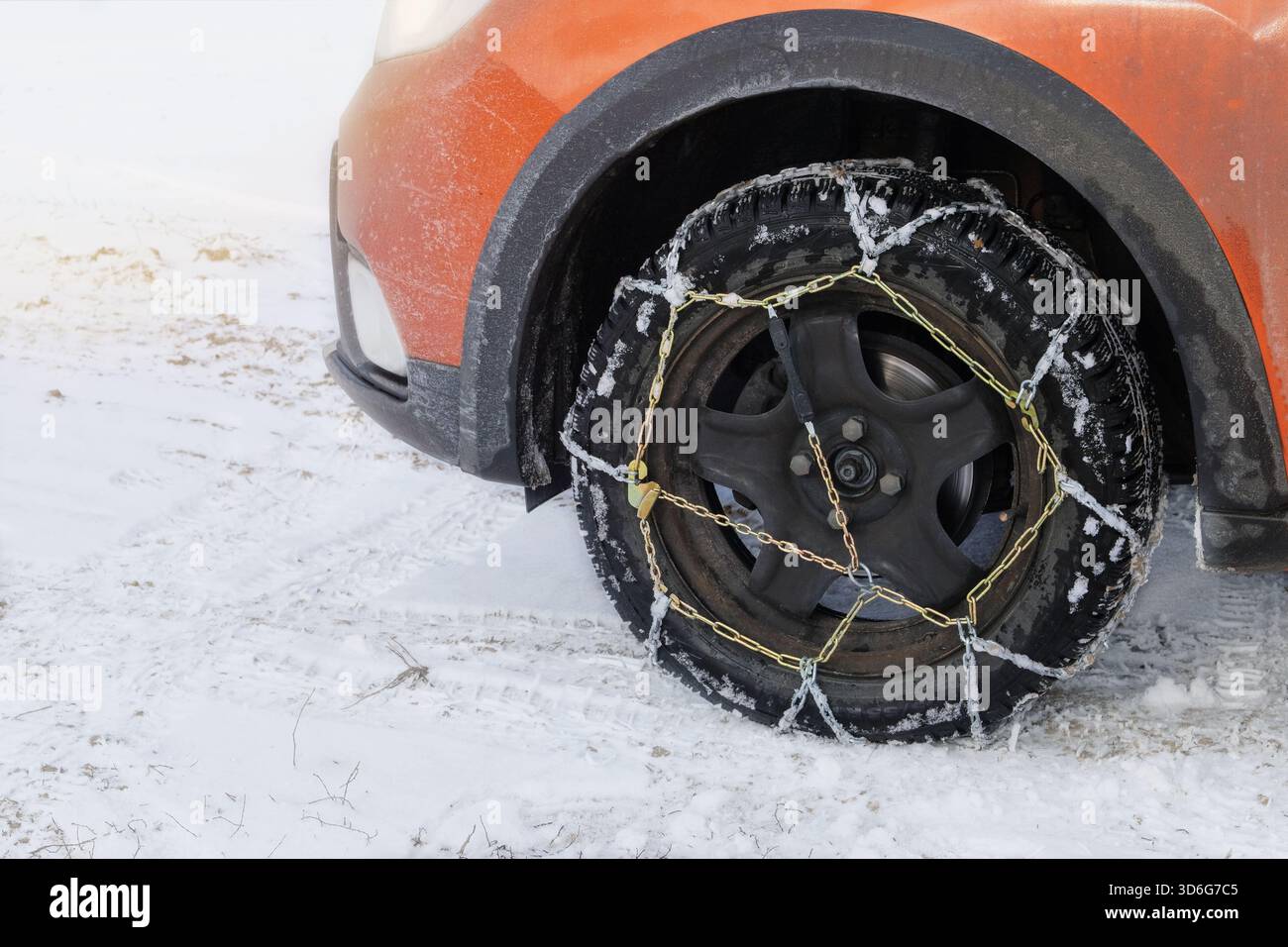 Équipement du véhicule pour le tout-terrain et les intempéries. Chaînes sur roue de voiture orange en hiver en plein air. Banque D'Images
