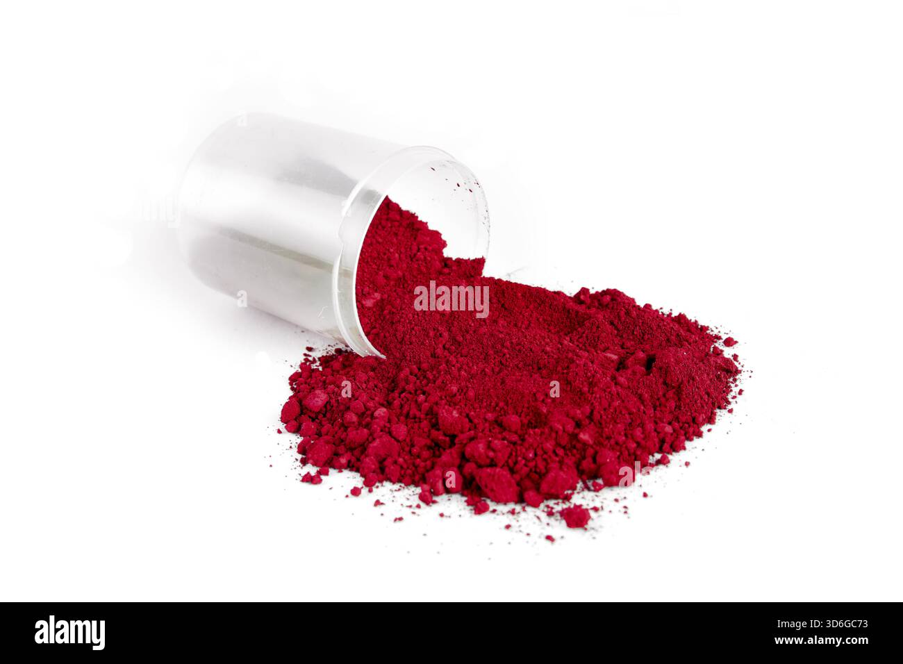 Un récipient renversé, renversant de la poudre rouge vif sur une surface blanche, mettant en valeur la couleur vive et la texture de la substance. Banque D'Images