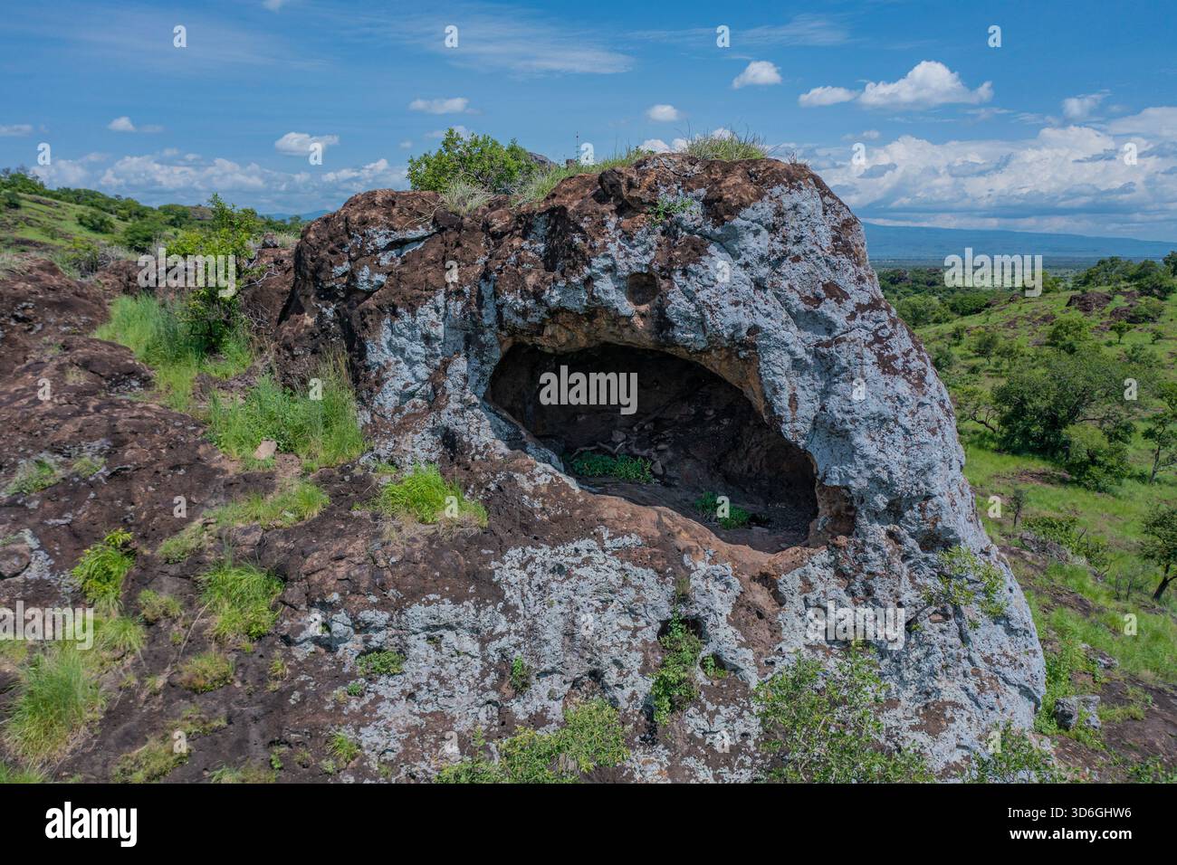 Vue aérienne de la grotte Napedet, sa surface texturée contrastant avec la végétation verte vibrante, une grotte cachée offrant un aperçu de la landsca Banque D'Images