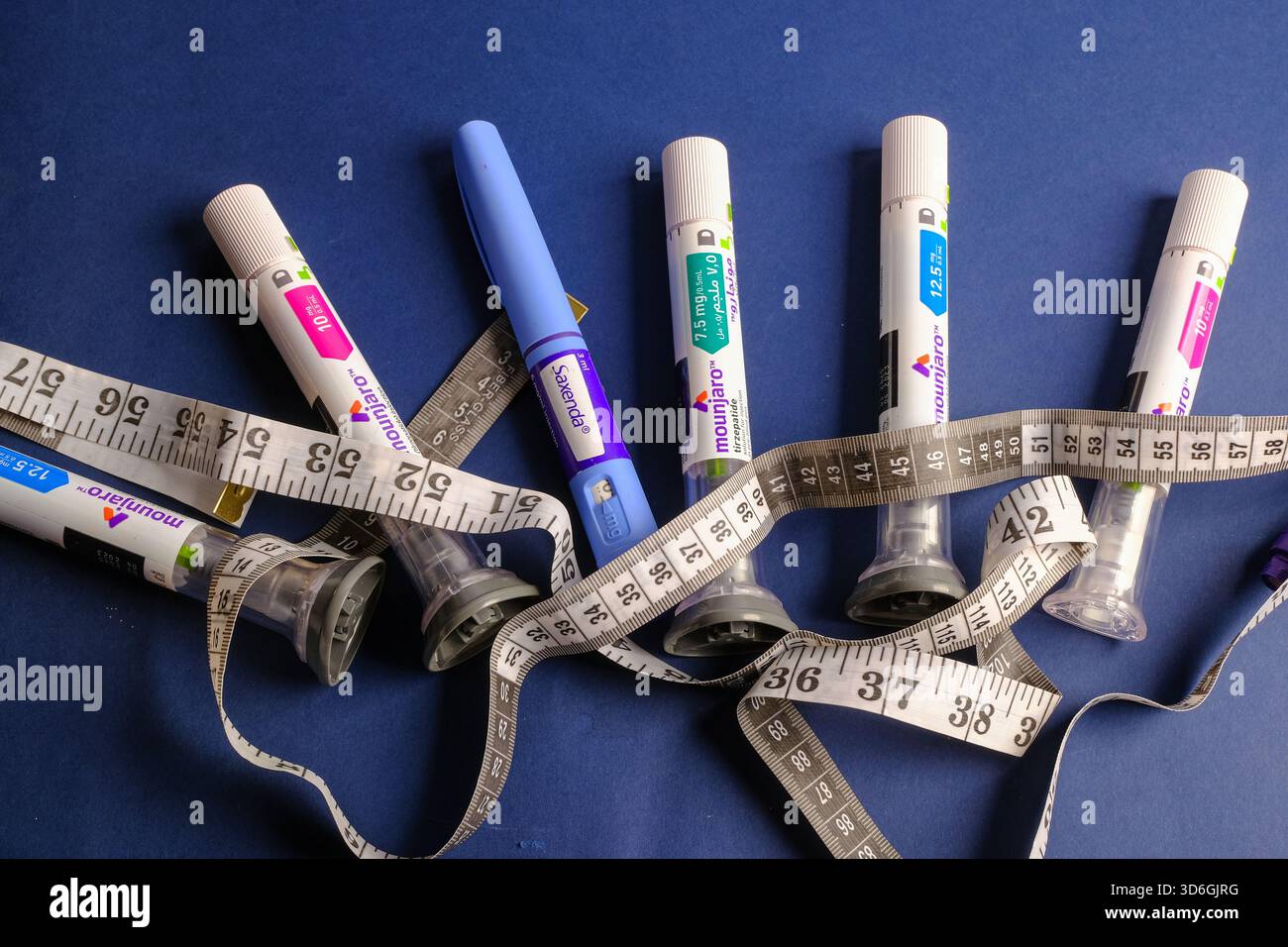 Mounjaro et les stylos d'injection de diabète entrelacés avec ruban à mesurer symbolisant le voyage de perte de poids Banque D'Images