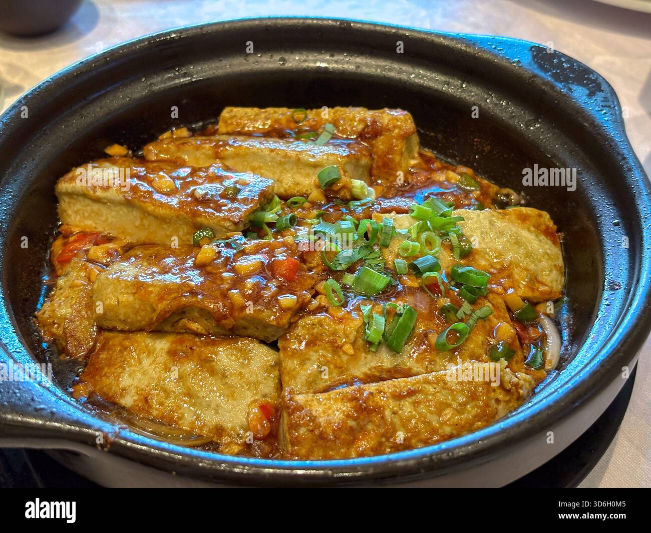 Plat de tofu noir frit servi dans une casserole en argile foncée, garni d'oignons verts et d'une sauce salée. Cuisine chinoise traditionnelle de Kaiping, Chine. Banque D'Images