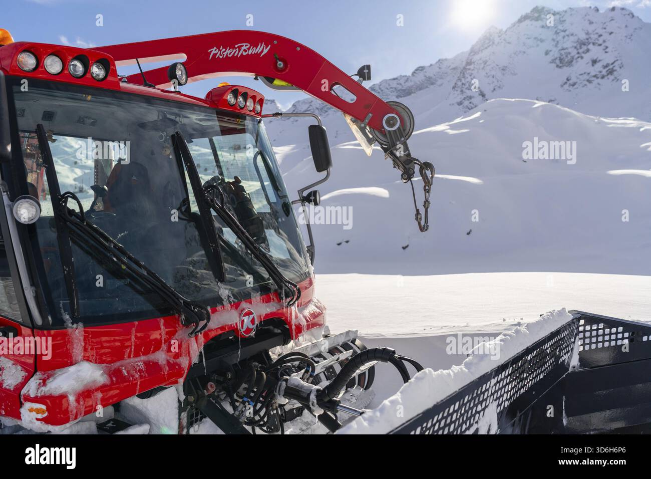 Ponte di Legno, Italie - 03.12.2023 : gros plan de la tondeuse à neige rouge avec bras mécanique, sur fond de montagnes enneigées. Le véhicule Banque D'Images
