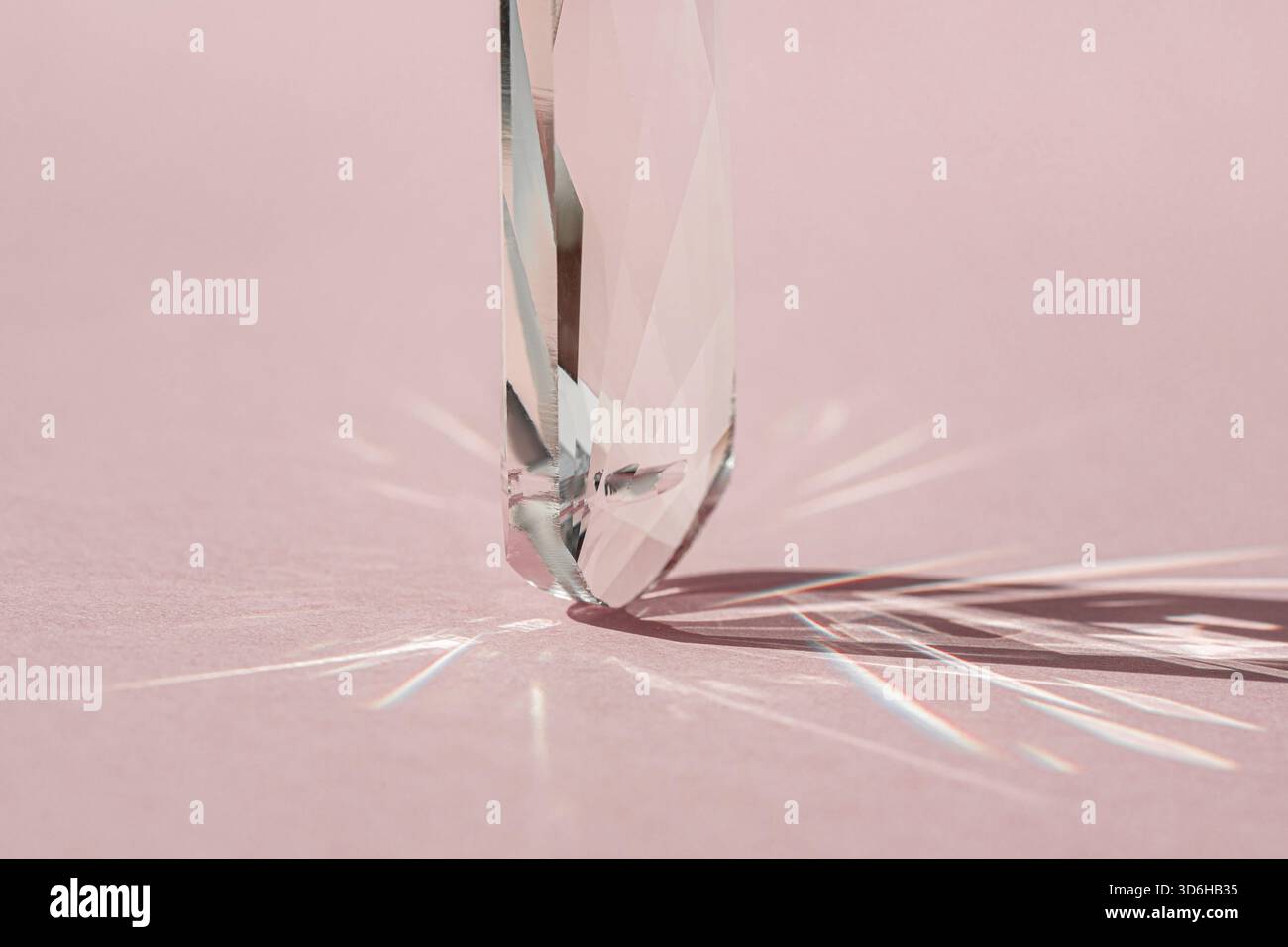 Prisme en cristal avec diffraction de lumière des couleurs du spectre et réflexion avec lumière tendance et ombres dures sur fond rose. Réflecteur de spectre lumineux Banque D'Images