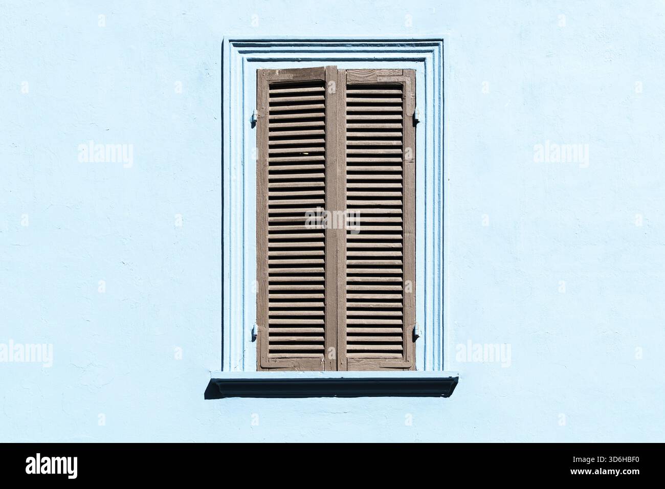 Volets gris sur la fenêtre contre un mur de couleur bleue. Extérieur ancien dans un village italien ou grec avec fenêtre fermée. Fenêtre vintage en bois avec gris Banque D'Images