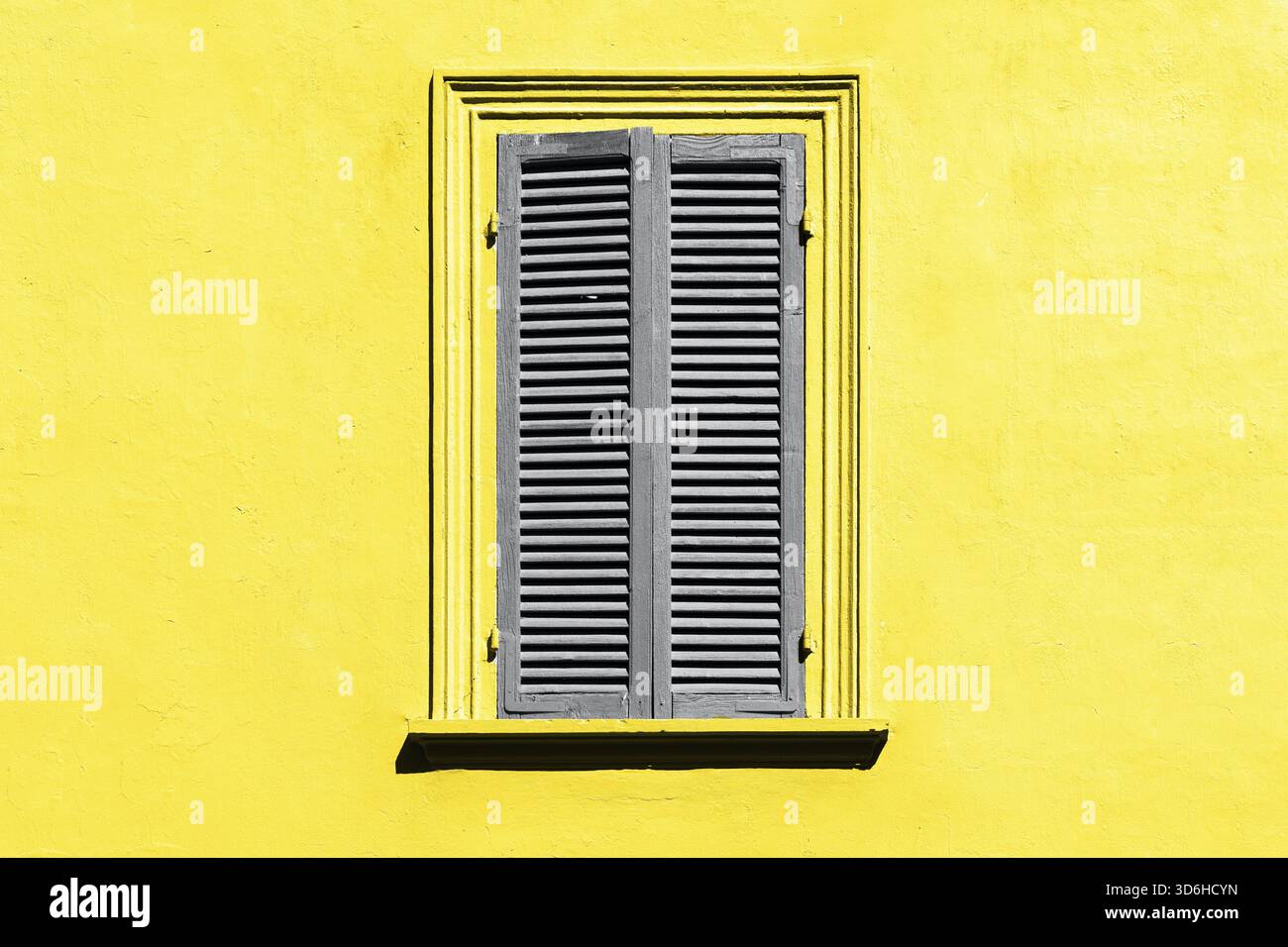 Couleur tendance de l'année 2021. Gris ultime et jaune illuminant. Volets gris sur la fenêtre contre un mur jaune. Extérieur de la vieille fenêtre en italie Banque D'Images