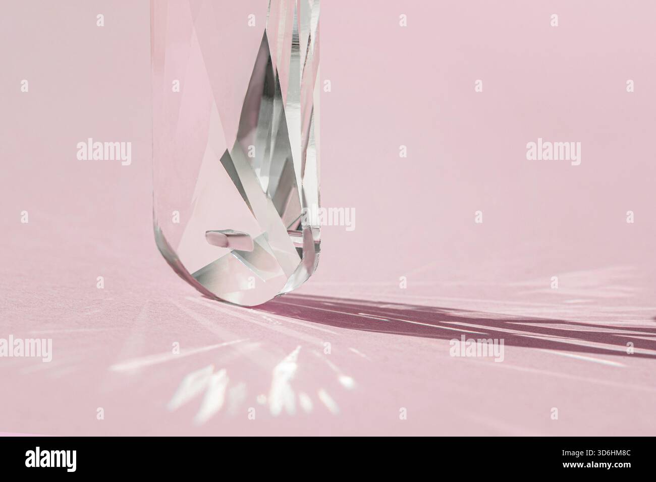 Prisme en cristal avec diffraction de lumière des couleurs du spectre et réflexion avec lumière tendance et ombres dures sur fond rose. Réflecteur de spectre lumineux Banque D'Images