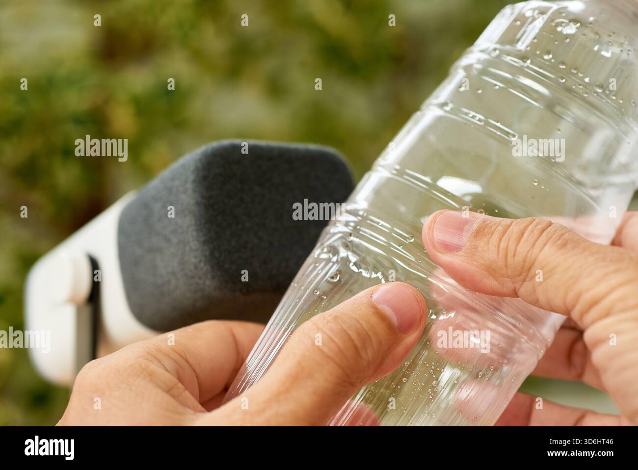Main pressant une bouteille d'eau en plastique pour créer des bruits de plissement ASMR. Banque D'Images