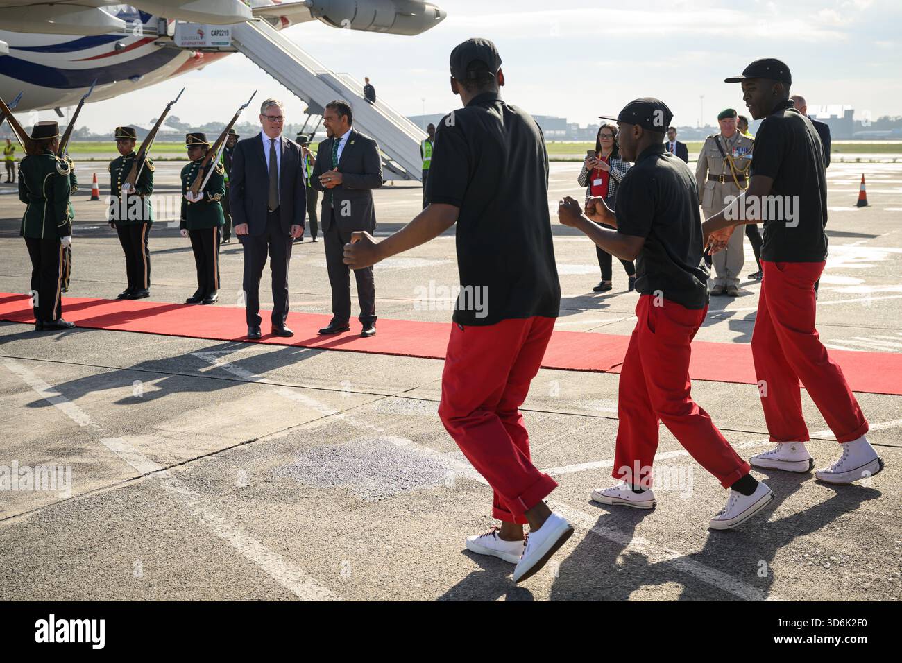 Le premier ministre Sir Keir Starmer (à gauche) regarde le groupe de danse Fire and Ivory Pantsula se produire alors qu’il est accueilli par un responsable sud-africain à son arrivée à l’aéroport international O.R. Tambo avant le sommet du G20 à Johannesburg, en Afrique du Sud. Date de la photo : vendredi 21 novembre 2025. Banque D'Images