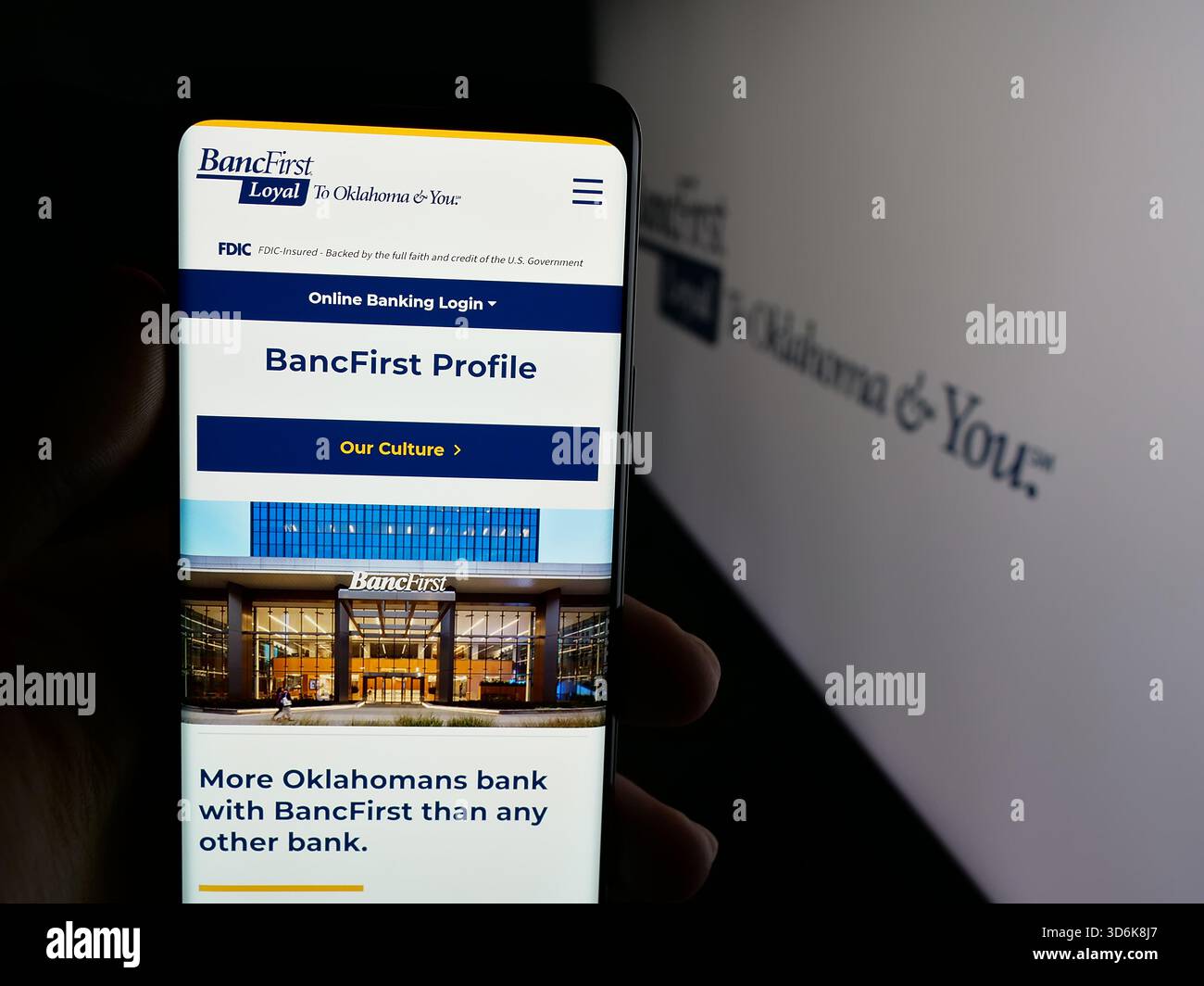 Stuttgart, Allemagne - 11-12-2025 : personne tenant le téléphone portable avec la page Web de la société financière américaine BancFirst Corporation sur l'écran devant le logo. Banque D'Images