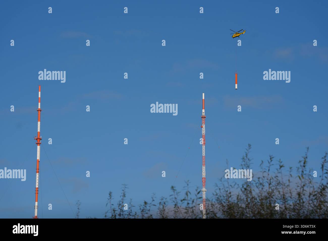 Hambourg, Allemagne. 21 novembre 2025. Un hélicoptère fait voler une antenne au sommet du nouveau mât de transmission de Norddeutscher Rundfunk (NDR) dans le quartier de Moorfleet. NDR construit un nouveau mât de transmission de 300 mètres de haut à Hamburg-Moorfleet pour remplacer son prédécesseur (l) vieux de 60 ans. Le nouveau mât sera la plus haute structure de Hambourg et fournira des signaux VHF, TV, DAB et DVB-T2 pour Hambourg et Schleswig-Holstein. Crédit : Marcus Brandt/dpa/Alamy Live News Banque D'Images