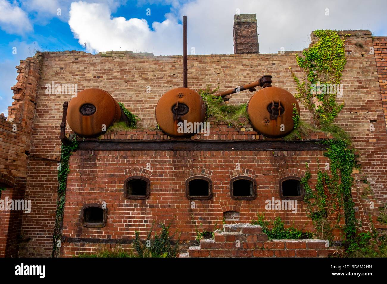 Trois chaudières cylindriques corrodées montées sur un mur de briques à Porth Wen briqueterie Banque D'Images