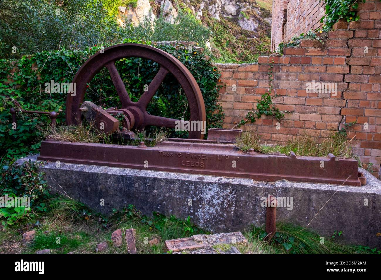 Vieilles machines rouillées à volant d'inertie à Porth Wen briques entourées de murs de briques Banque D'Images