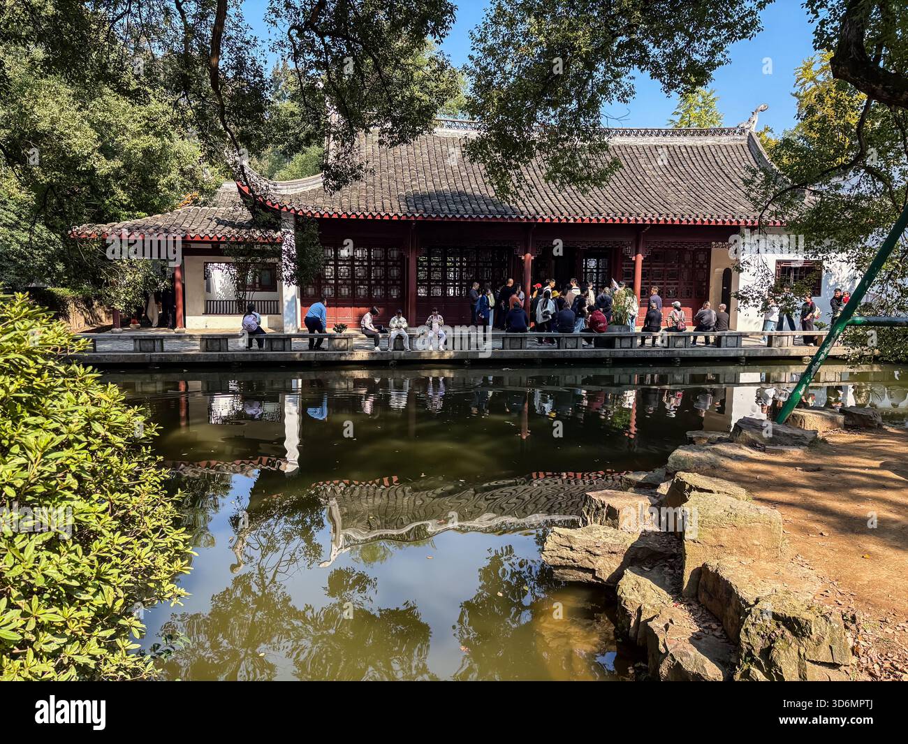 Yuelu Academy à Changsha, en Chine, se reflète dans un étang tranquille par une journée ensoleillée avec des visiteurs admirant l'architecture historique. Banque D'Images