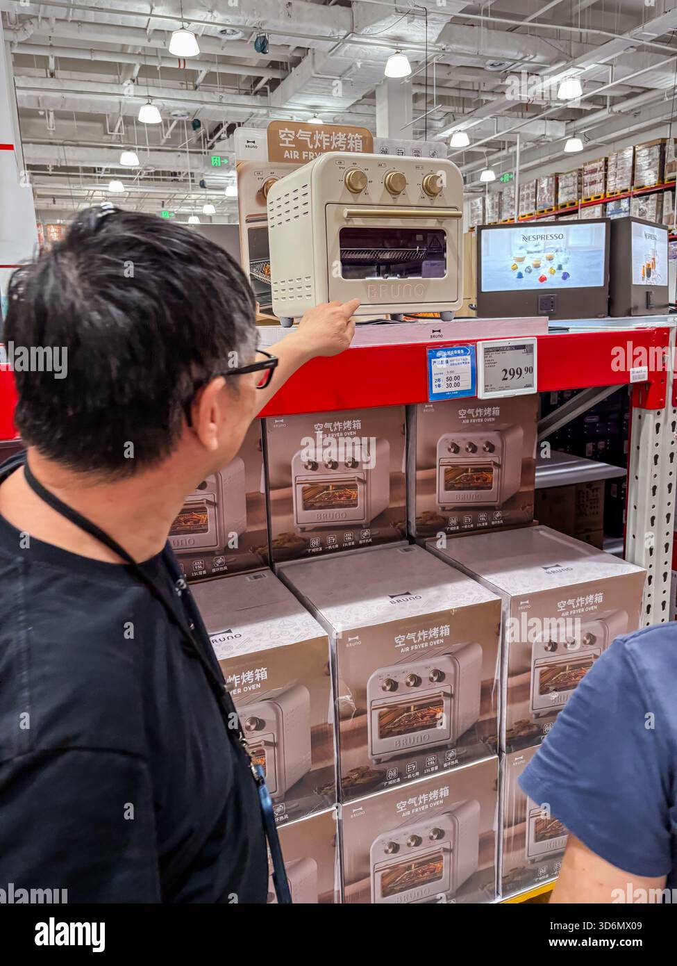 Un client inspecte un four de friteuse à air de la marque Bruno exposé dans un grand magasin de gros Sam's Club en Chine, mettant en avant un magasin d'électronique grand public Banque D'Images