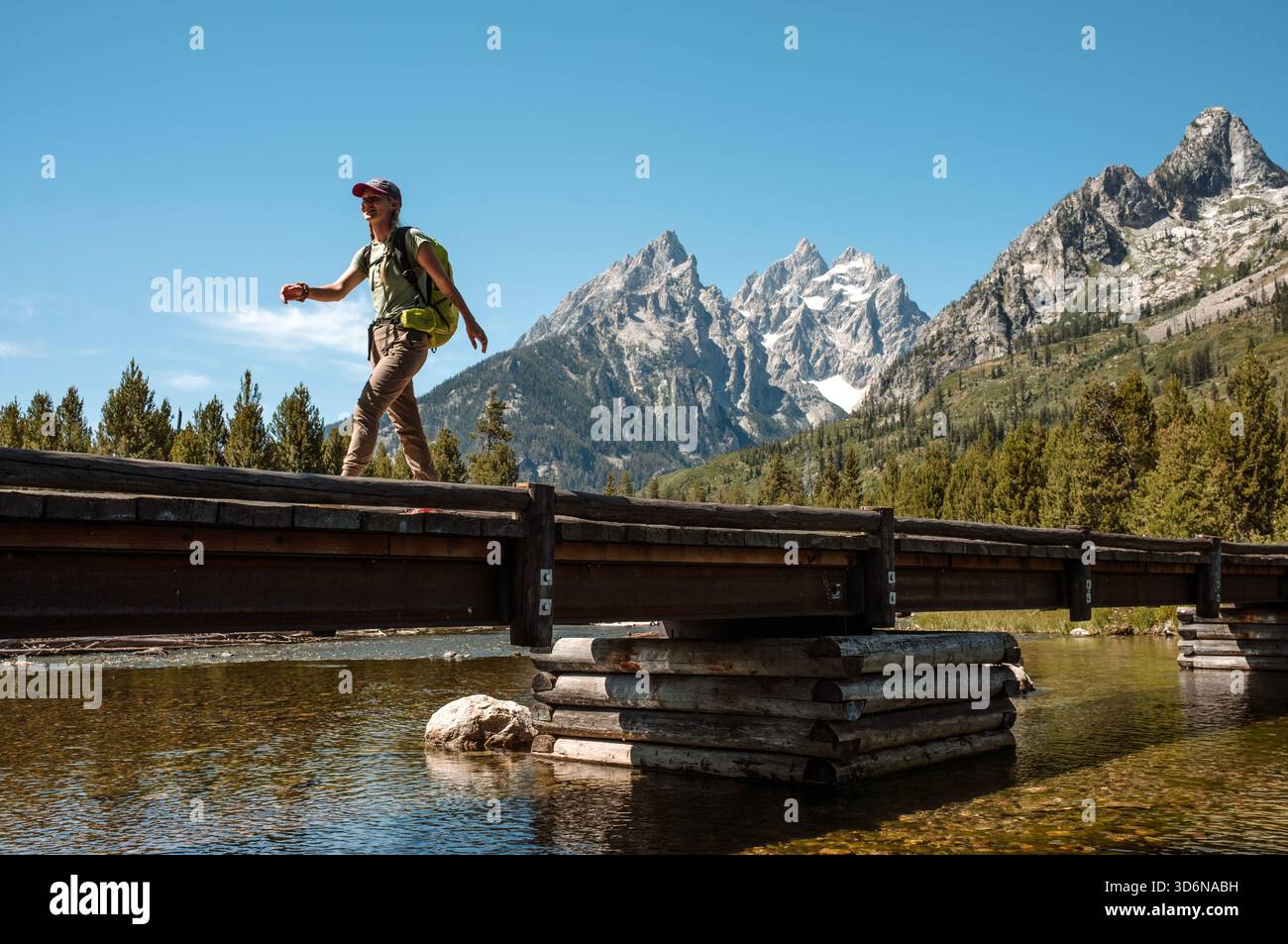Heureuse randonnée féminine sur le pont de sentier dans les Tetons du Wyoming Banque D'Images