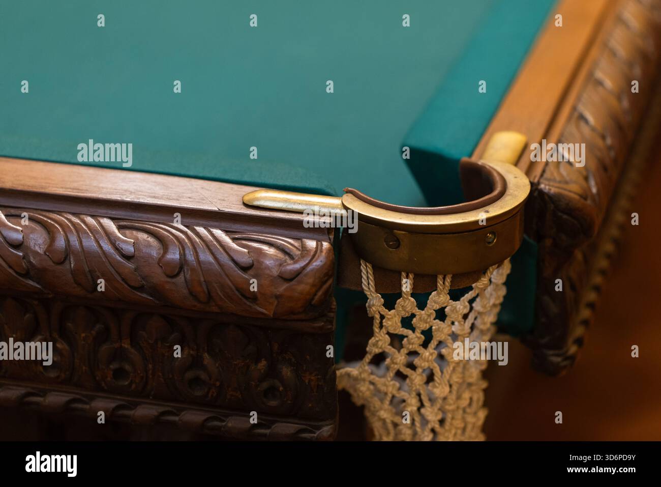 Photo rapprochée d'un bord de table de billard en bois sculpté orné avec une poche en laiton et un délicat filet blanc. Un savoir-faire riche et une élégance vintage Banque D'Images