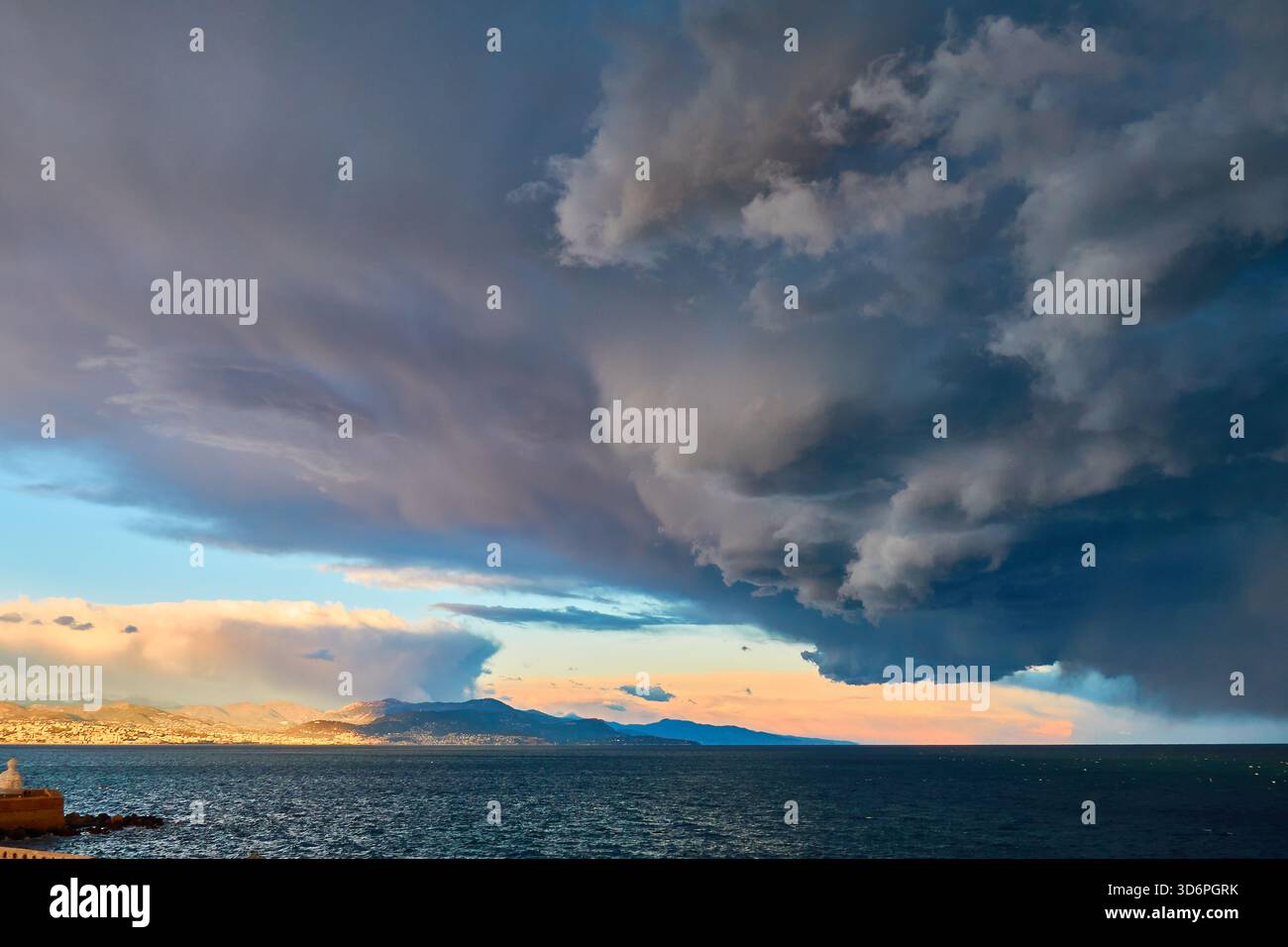Nuages de tempête spectaculaires au-dessus de la mer calme au coucher du soleil derrière Mountain Horizon Banque D'Images