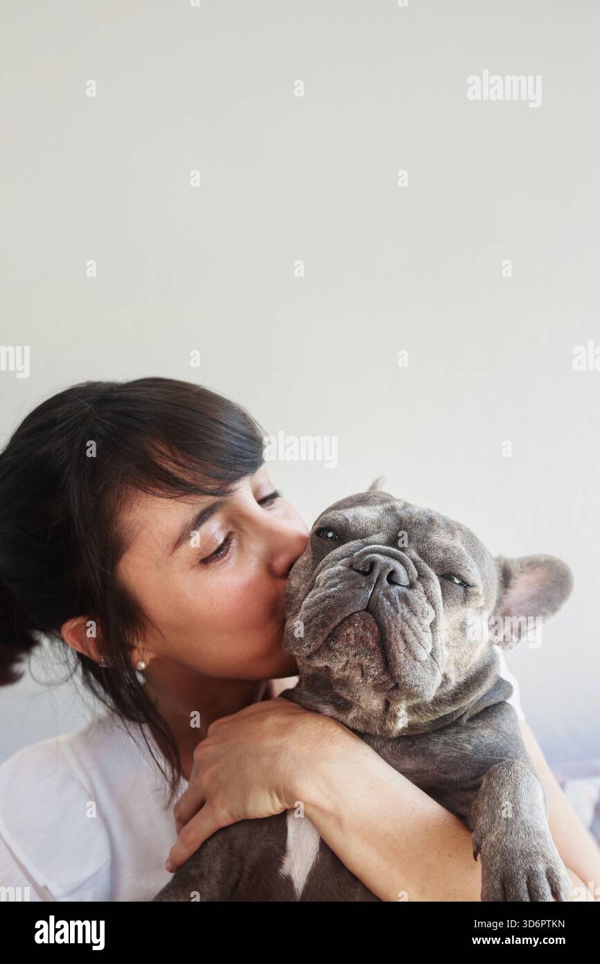 Femme Latina embrassant son bouledogue français sur fond blanc. PET - propriétaire relation d'amour Banque D'Images