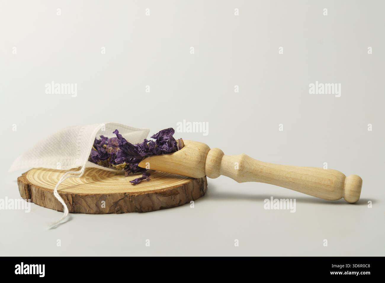 Fleurs de mauve violette séchées dans un sachet de thé réutilisable avec une cuillère en bois sur une tranche de bois, préparant une tisane Banque D'Images