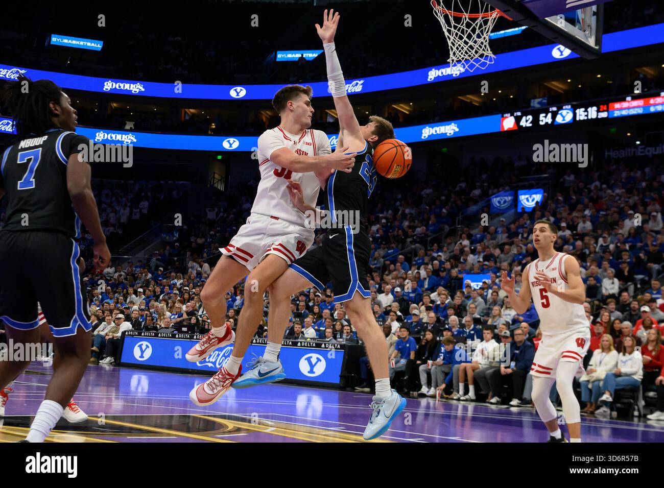 Wisconsin forward Nolan Winter, center left, passes the ball to guard Jack Janicki (5) around the defense of BYU guard Dawson Baker, center right, during the second half of an NCAA college basketball game, Friday, Nov. 21, 2025, in Salt Lake City. (AP Photo/Tyler Tate) Banque D'Images