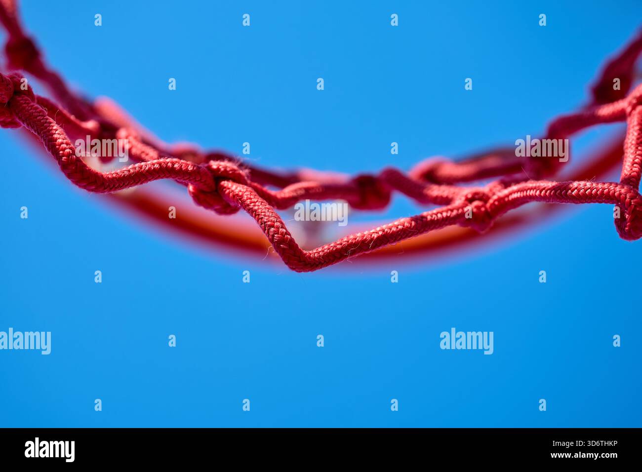 Un filet de basket rouge dessiné contre un ciel dégagé. Banque D'Images