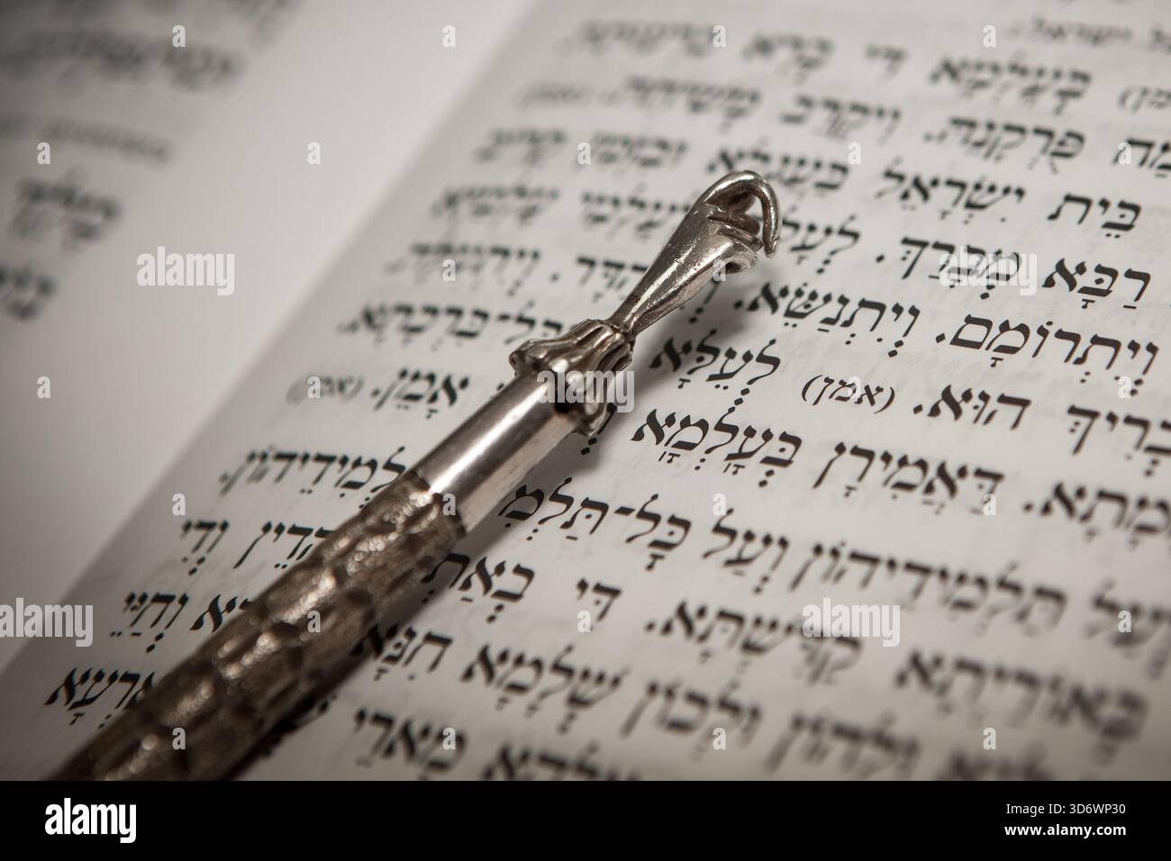 Gros plan d'un Yad pointer argenté traditionnel sur un texte biblique hébreu, symbolisant la foi juive et la lecture de la Torah à Jérusalem. Banque D'Images