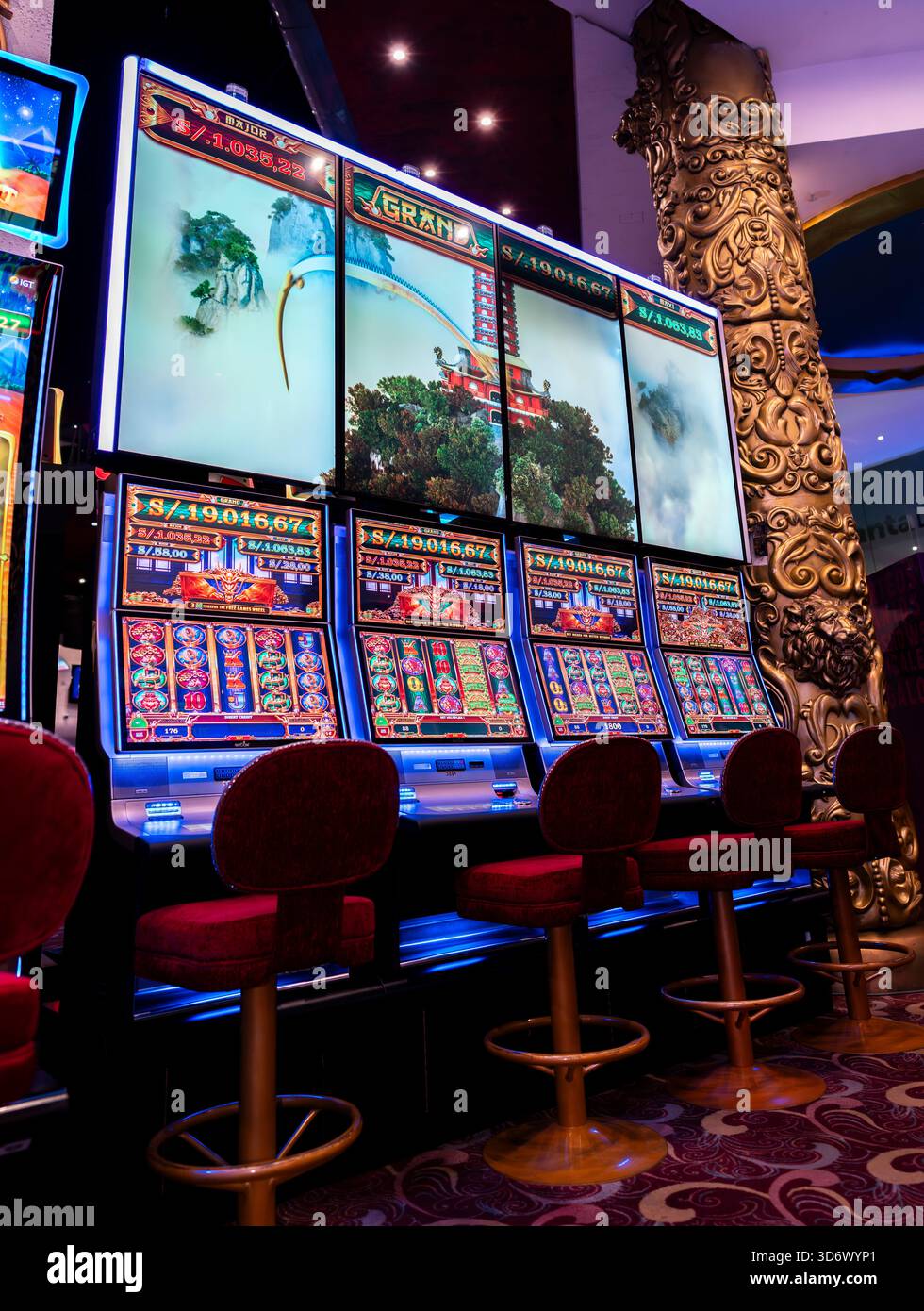 Rangée de machines à sous modernes à thème asiatique avec de grands écrans numériques et des chaises rouges dans un intérieur de casino, idéal pour les jeux d'argent, le tourisme, la vie nocturne et en Banque D'Images