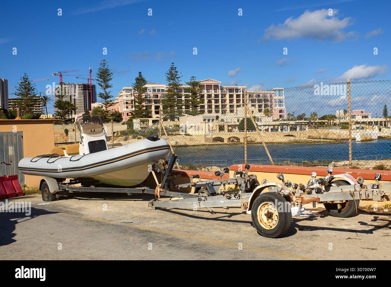 Un bateau GONFLABLE RIB sur une remorque se trouve stationné près de la mer contre la toile de fond des hôtels de luxe, des grues de construction, et la Méditerranée bleue Banque D'Images