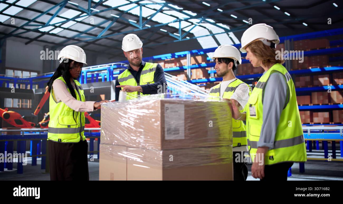 Le personnel de l'entrepôt reçoit des instructions sur les techniques efficaces d'emballage des palettes. Responsable de bureau supervisant une équipe diversifiée Banque D'Images
