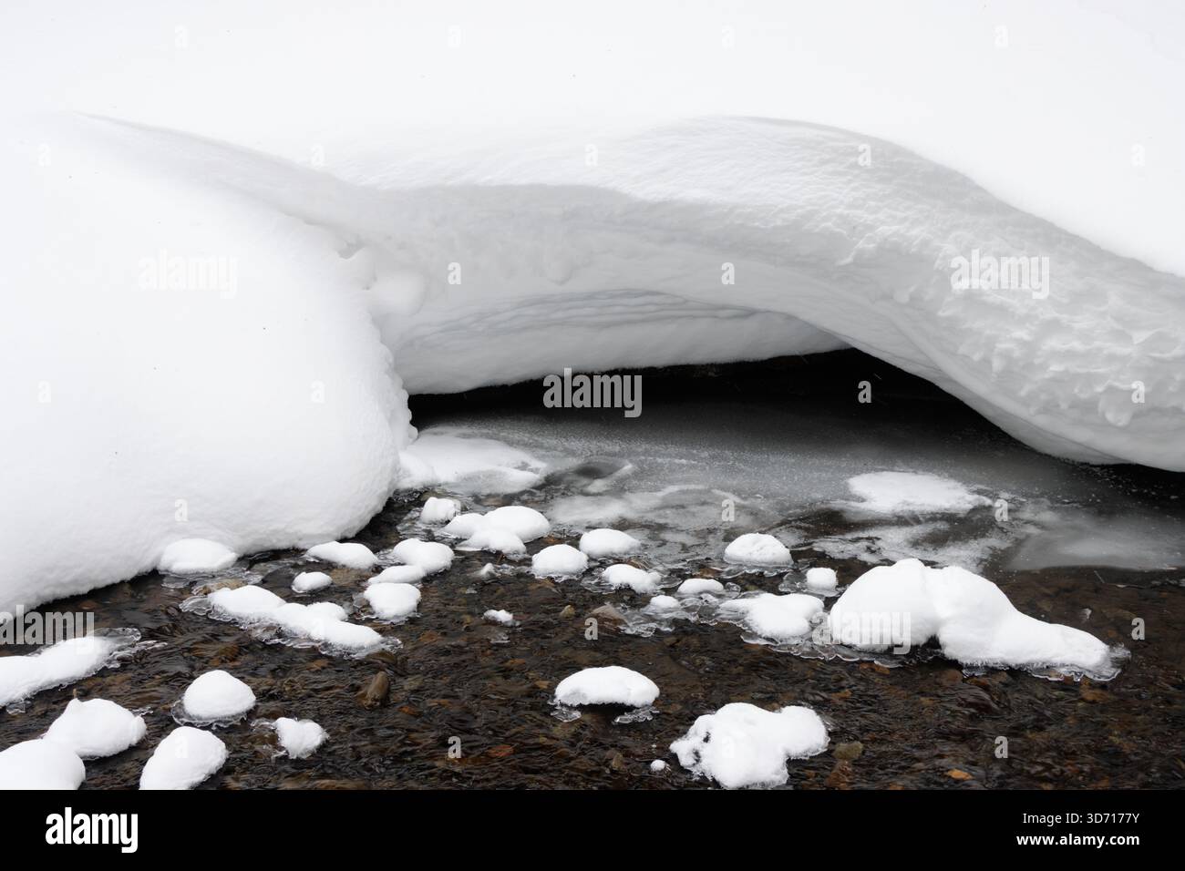 Eau coulant par la neige blanche profonde sur la rive, Hokkaido, Japon Banque D'Images