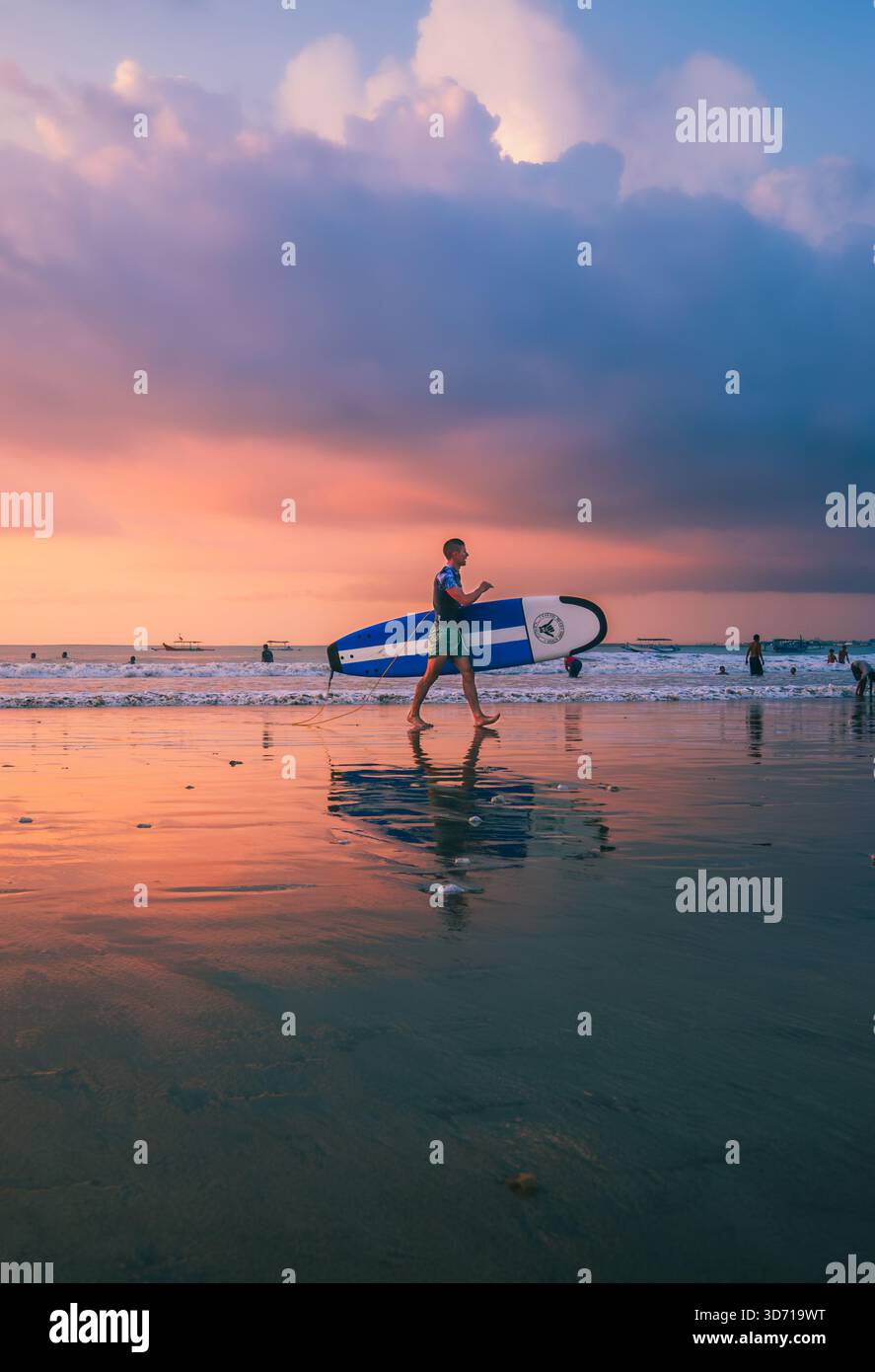 Les surfeurs se promènent tranquillement sur Jimbaran Beach dans l'après-midi du 5 octobre 2025, Bali, Indonésie Banque D'Images