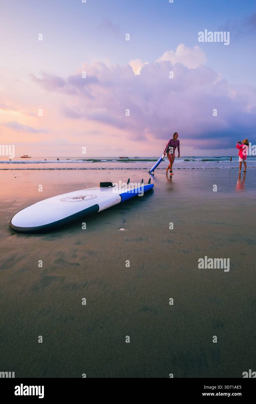 Les surfeurs se promènent tranquillement sur Jimbaran Beach dans l'après-midi du 5 octobre 2025, Bali, Indonésie Banque D'Images