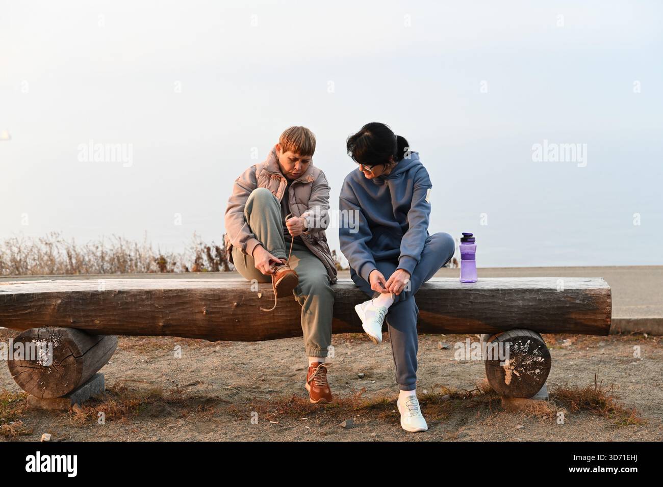 Une femme russe de 50 ans et son amie de 60 ans sont assises sur un banc en enfilant des baskets et en attachant leurs lacets, se préparant pour le sport. Banque D'Images