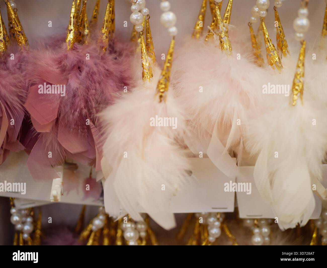 Ornements de plumes roses et blanches douces suspendus sur l'affichage du magasin, texture moelleuse pour le décor de Noël, vente au détail festive, décoration de vacances saisonnière Banque D'Images