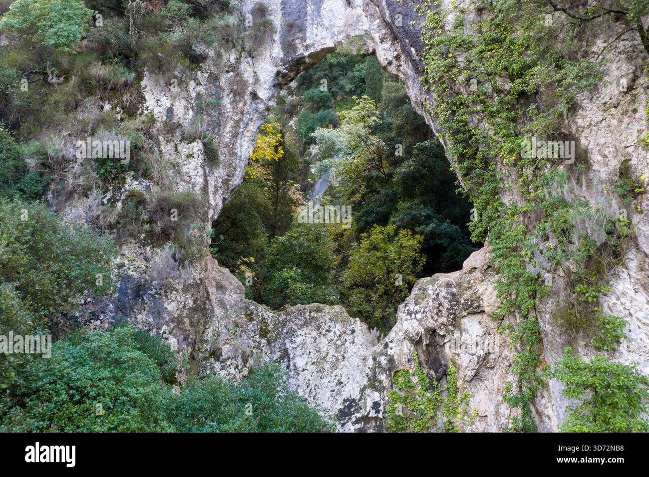 Fenêtre en arc de roche naturelle encadrant un canyon forestier caché à Corfou Grèce drone aérien vue rapprochée de la formation géologique de calcaire Banque D'Images