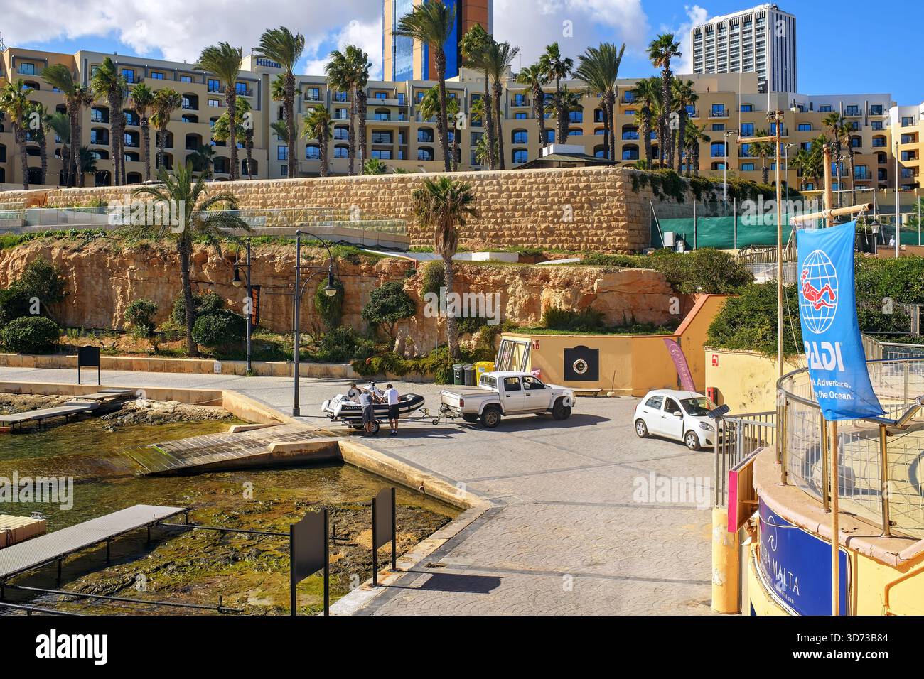 St.Julian's, Malte - 11.11.2025, des hommes transportent un bateau pneumatique de l'eau à la cale de la marina de Portomaso, face aux hôtels du front de mer Banque D'Images