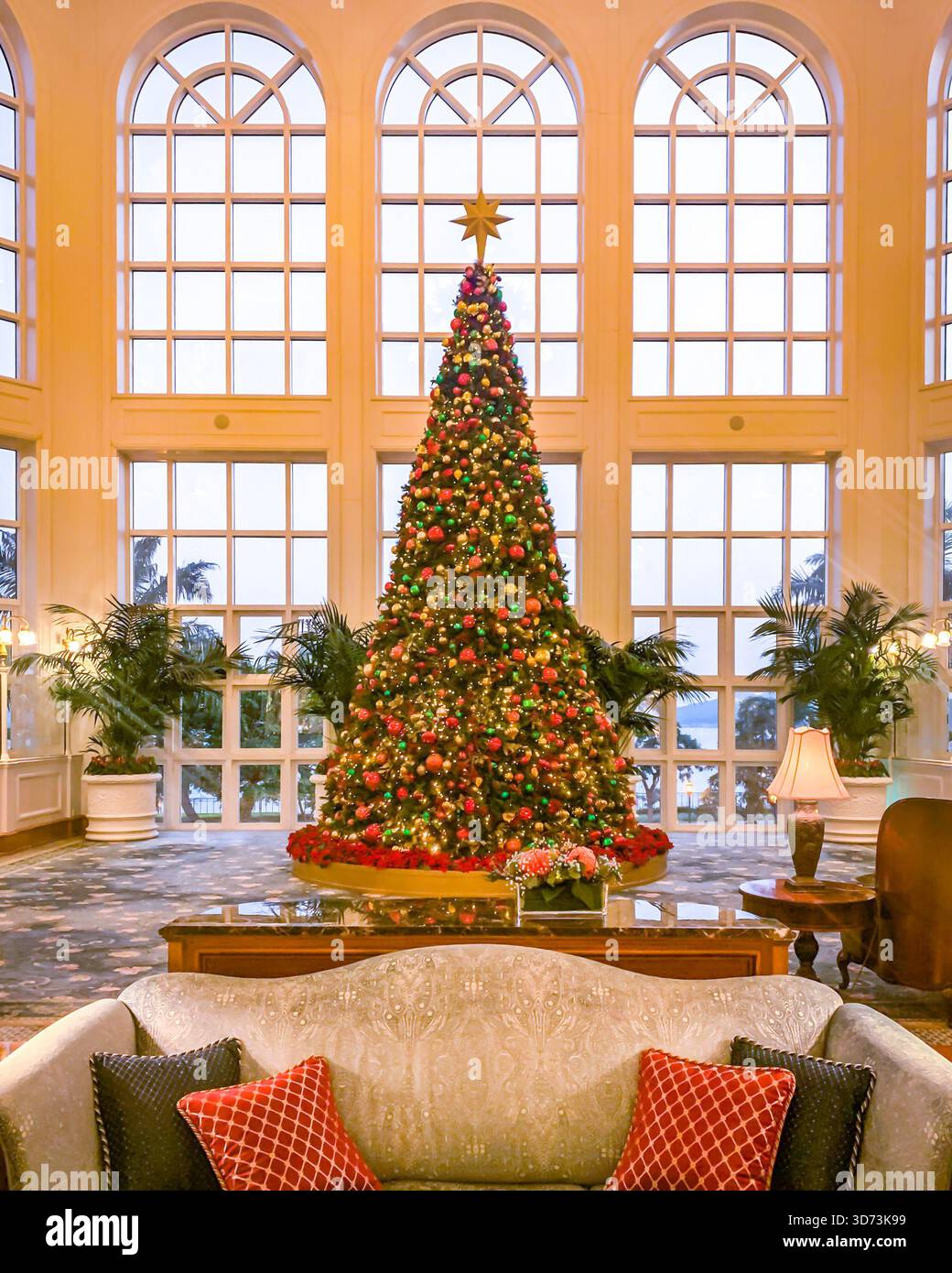 Un sapin de Noël joliment décoré se dresse dans un hall luxueux, créant une atmosphère chaleureuse et accueillante pour les vacances Banque D'Images