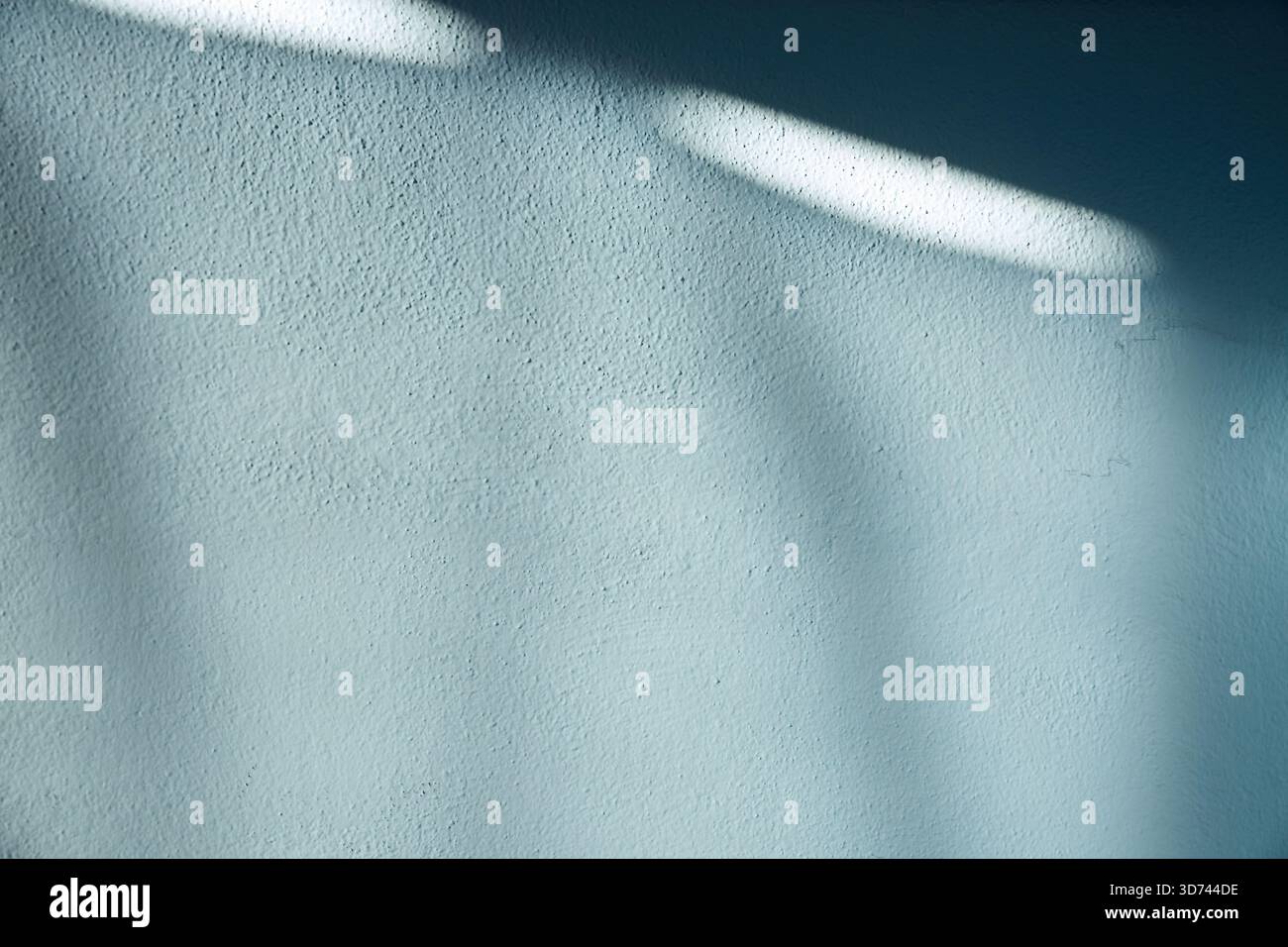 Un mur bleu doux avec une texture fine et des ombres naturelles créant des formes abstraites et allongées sur toute la surface. Idéal pour la conception graphique, mise en page moderne Banque D'Images