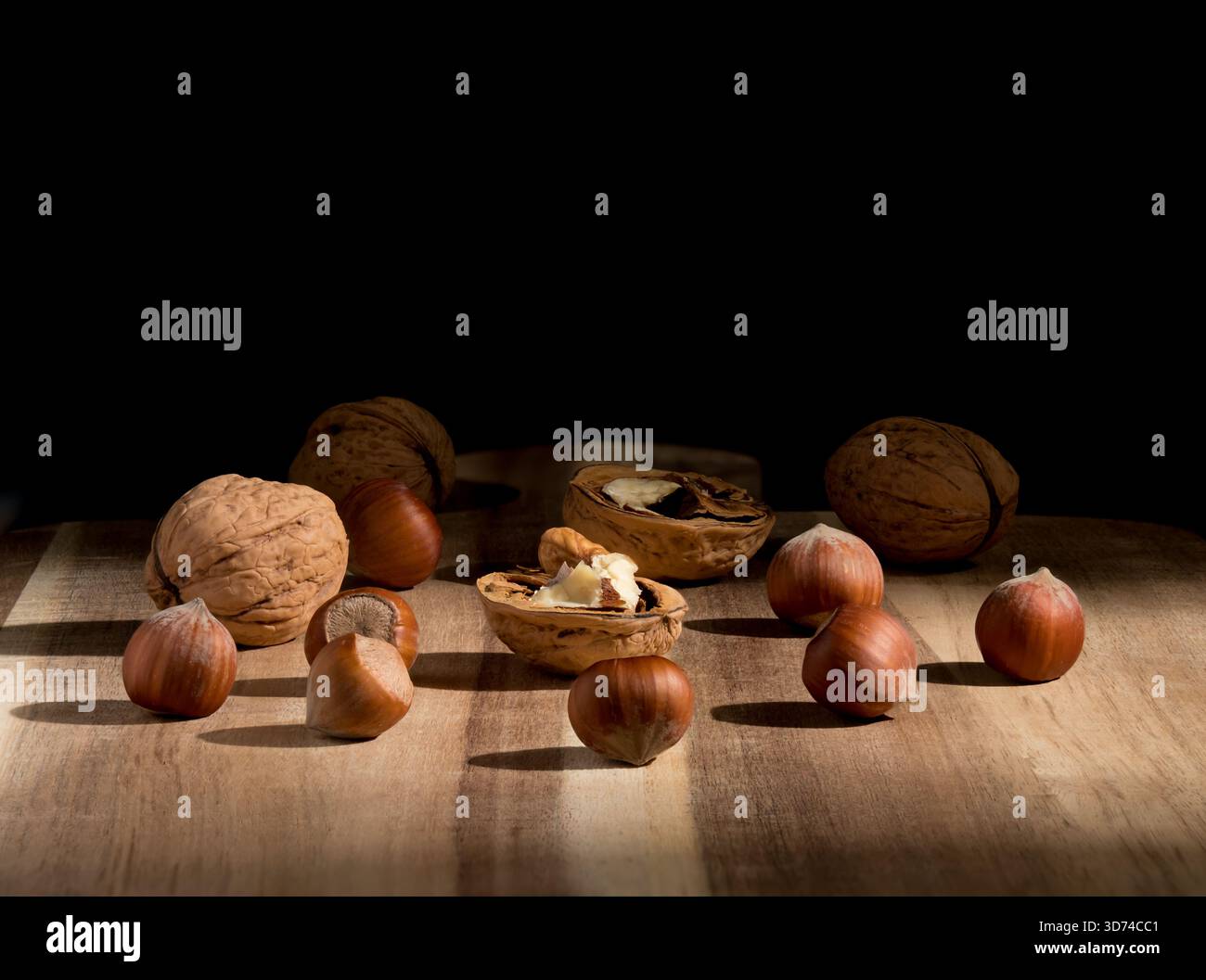 Noix et noisettes, un bâton de vanille sur une table en bois, un fond discret, un papier peint sur le thème de Noël, illuminé par une lumière latérale Banque D'Images