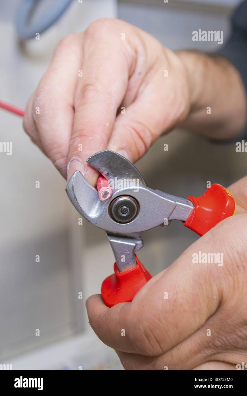 L'électricien utilise des pinces pour couper le fil rouge en gros plan Banque D'Images