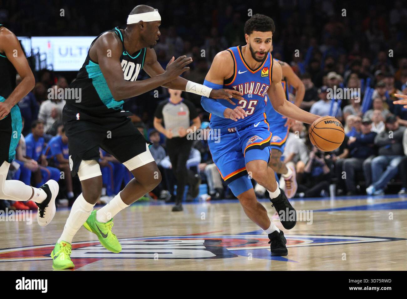 Oklahoma City Thunder guard Ajay Mitchell (25) drives against Portland Trail Blazers center Duop Reath, left, during the second half of an NBA basketball game Sunday, Nov. 23, 2025, in Oklahoma City. (AP Photo/Nate Billings) Banque D'Images