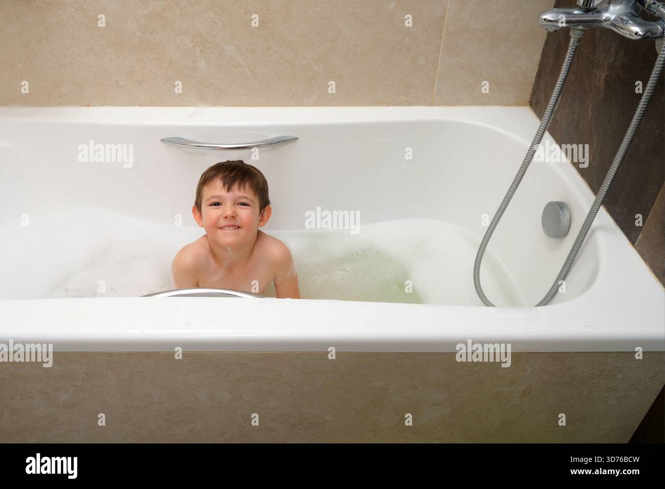 Garçon enfant souriant profitant d'un bain moussant ludique dans une salle de bain moderne, montrant la joie, l'hygiène et les moments quotidiens de routine familiale. Enfant âgé de 4 ans (fou Banque D'Images