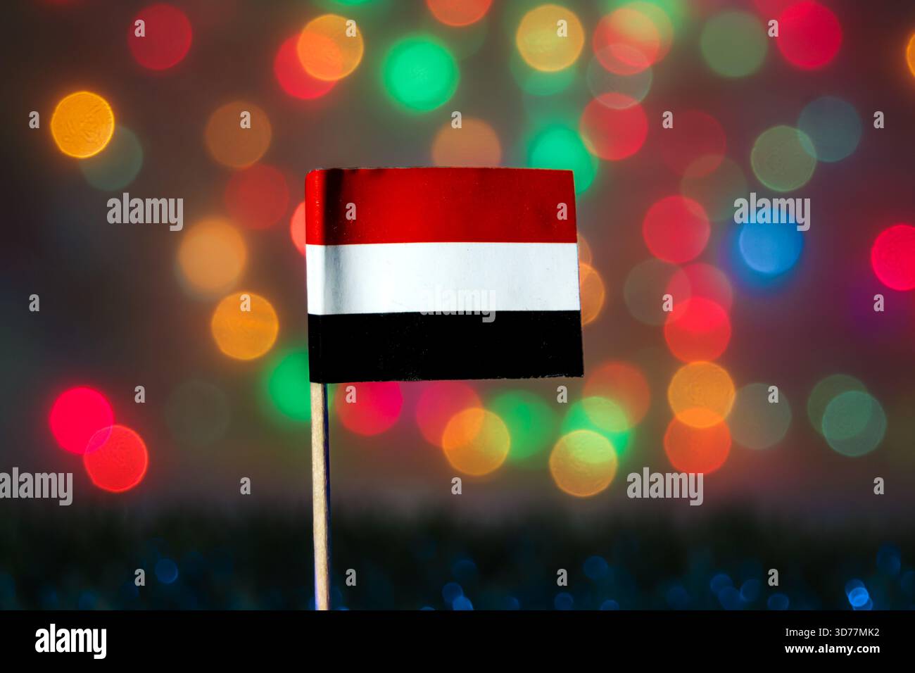 Drapeau du Yémen fixé contre des lumières bokeh multicolores brillantes, reflétant le jour de l'unité, la fierté nationale, les thèmes festifs et l'identité culturelle du moyen-Orient. Banque D'Images