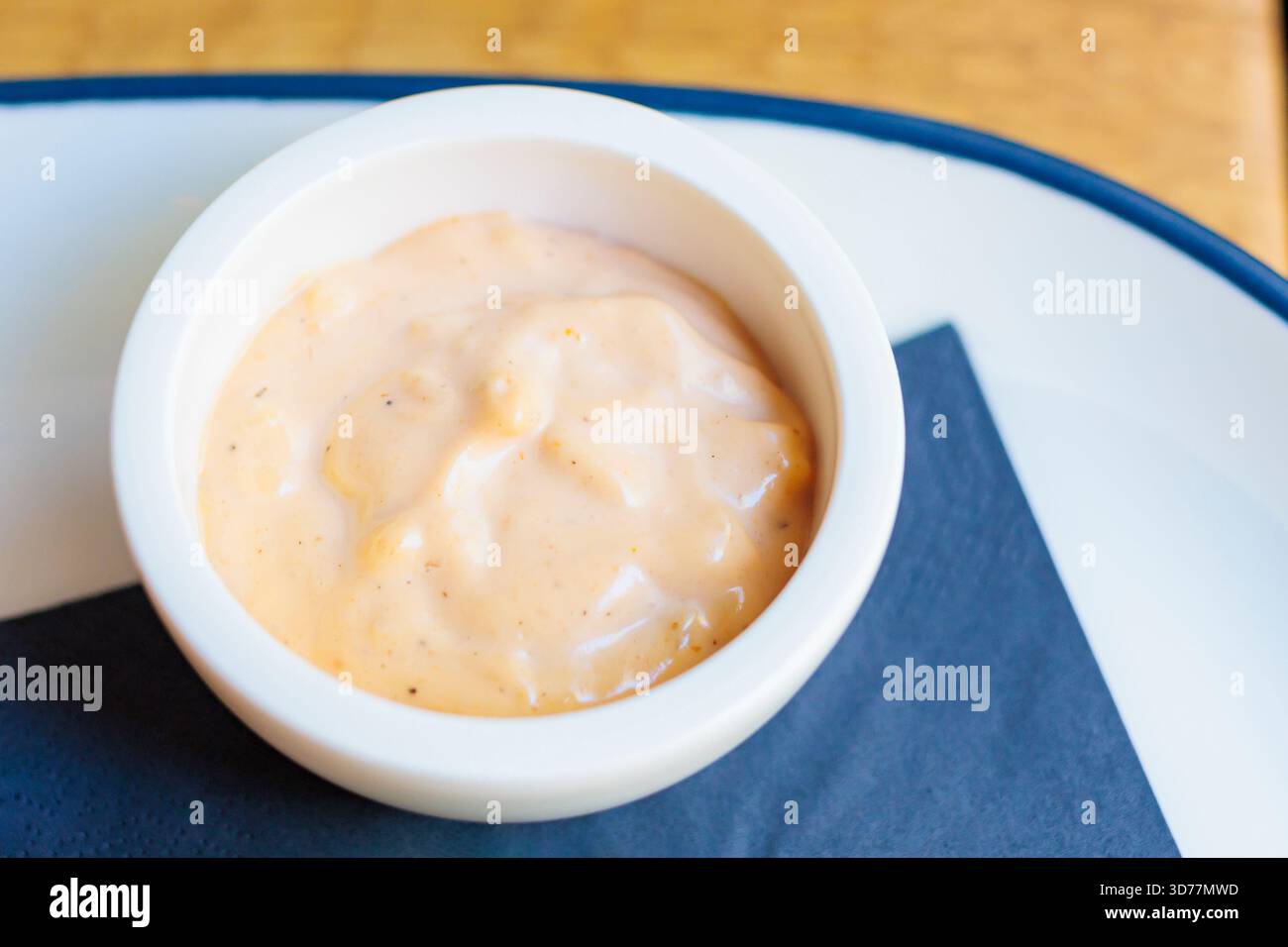 Sauce crémeuse servie dans un petit bol sur une assiette avec une serviette foncée Banque D'Images