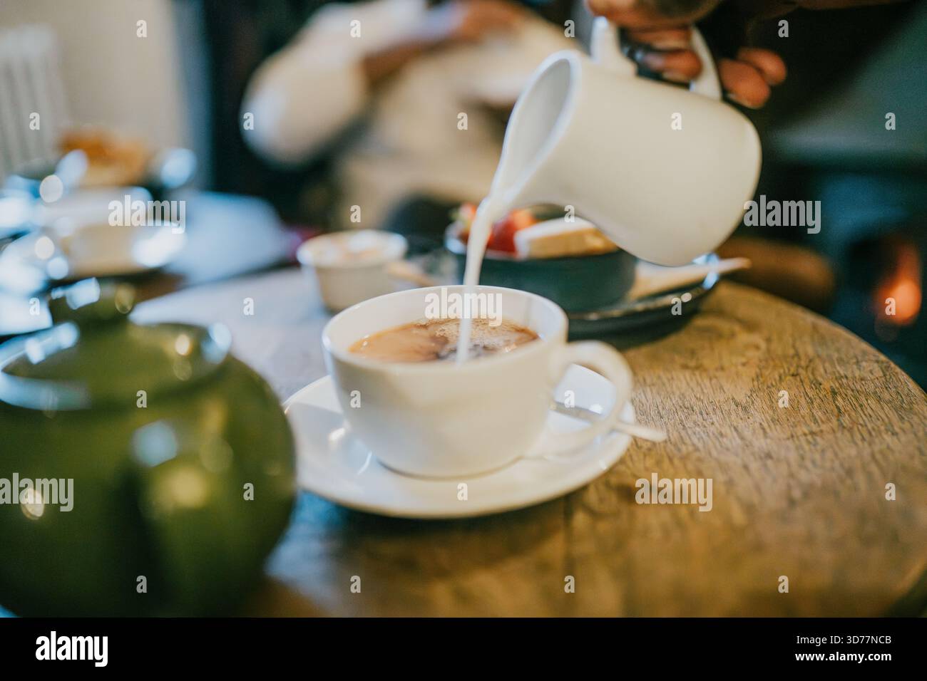 Une tasse blanche de café est versée dans une tasse. La tasse est sur une table en bois Banque D'Images