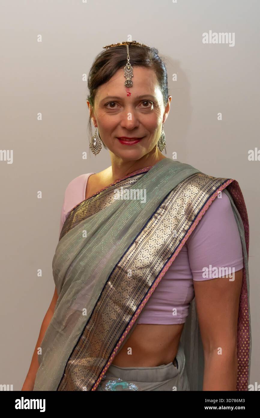 Une femme pose dans un sari indien avec des bijoux, debout dans un cadre de studio neutre Banque D'Images