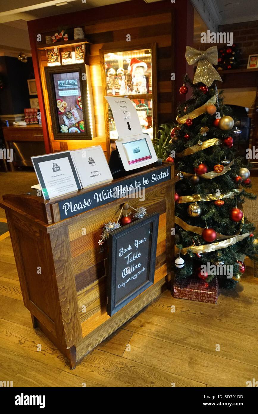 Entrée festive du restaurant avec stand d'hôtesse et sapin de Noël décoré, créant un accueil chaleureux et saisonnier pour les clients. Édimbourg, Écosse Banque D'Images