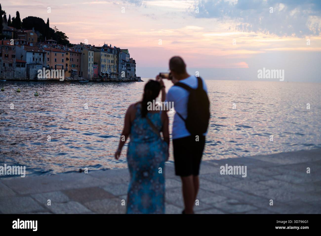 Couple profite d'une promenade romantique en soirée sur le front de mer alors que le soleil se couche sur Rovinj, Croatie Banque D'Images