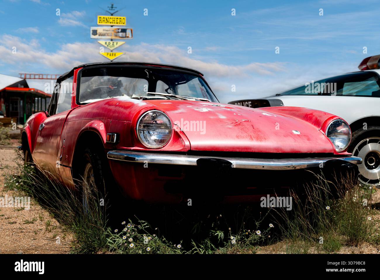 Cet ancien Triumph Spitfire abandonné, peint en rouge délavé, repose dans une junkyard du désert le long de l'historique route 66 des États-Unis en Arizona. Banque D'Images